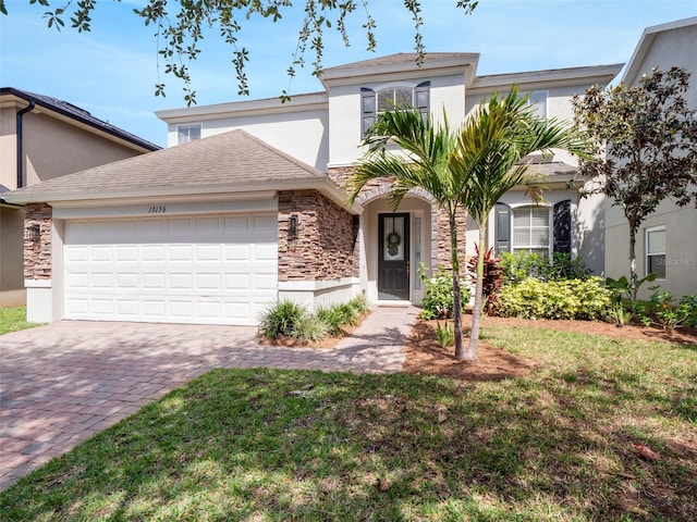 13156 Hatherton Cir, Orlando, FL 32832 - view of front facade featuring stucco siding, stone siding, decorative driveway, and an attached garage