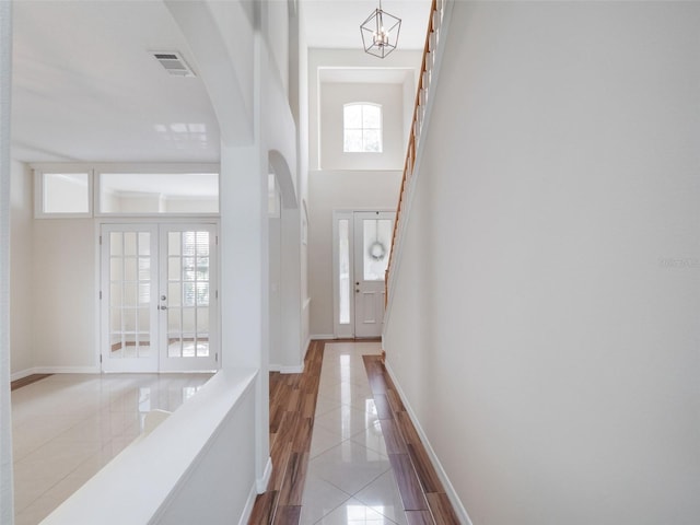 13156 Hatherton Cir, Orlando, FL 32832 - hall featuring tile patterned flooring, baseboards, arched walkways, a towering ceiling, and french doors