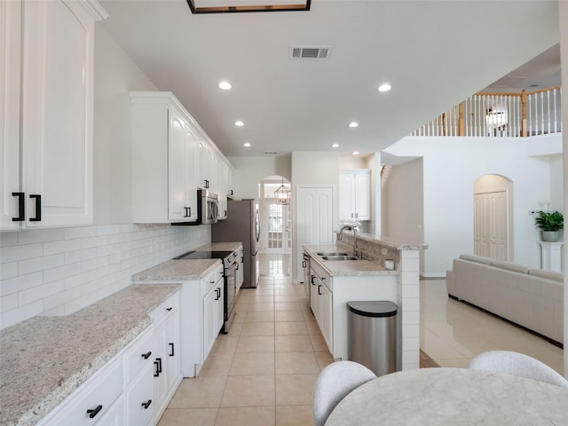 13156 Hatherton Cir, Orlando, FL 32832 - kitchen featuring arched walkways, a sink, light tile patterned flooring, stainless steel appliances, and recessed lighting