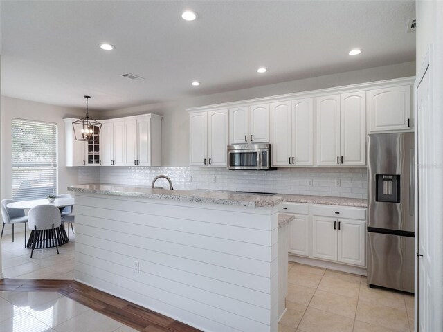 13156 Hatherton Cir, Orlando, FL 32832 - kitchen featuring appliances with stainless steel finishes, a chandelier, white cabinets, decorative backsplash, and a center island