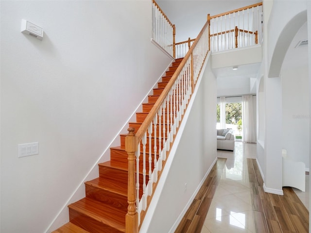 13156 Hatherton Cir, Orlando, FL 32832 - staircase with arched walkways, baseboards, a high ceiling, and tile patterned flooring