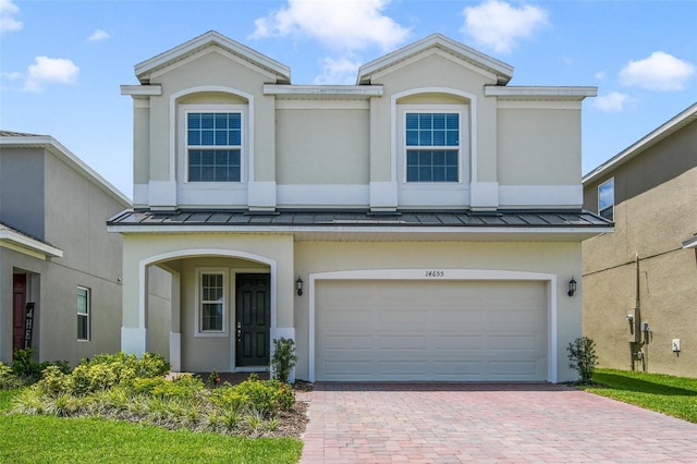14655 Erice Ave, Clermont, FL 34714 - view of front of property featuring a standing seam roof, decorative driveway, an attached garage, and stucco siding