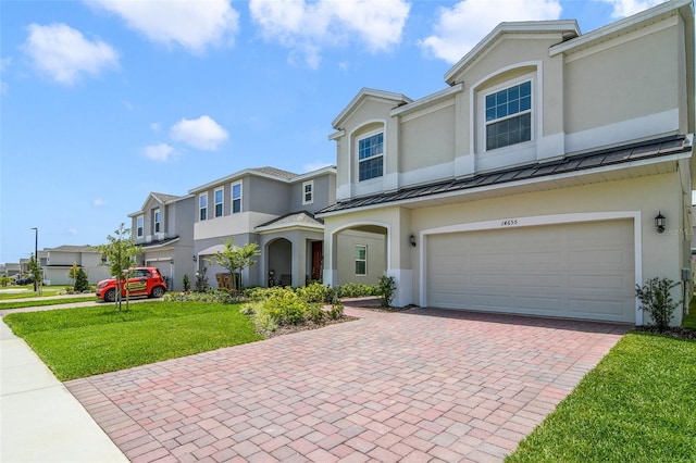 14655 Erice Ave, Clermont, FL 34714 - view of property featuring a standing seam roof, stucco siding, decorative driveway, and an attached garage
