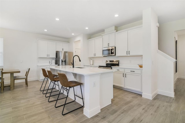 14655 Erice Ave, Clermont, FL 34714 - kitchen with appliances with stainless steel finishes, light wood-style floors, a sink, a kitchen bar, and recessed lighting