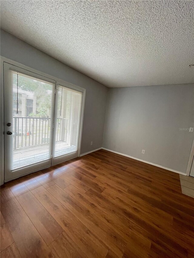 238 Afton Sq Unit 204, Altamonte Springs, FL 32714 - spare room featuring wood finished floors, healthy amount of natural light, a textured ceiling, and baseboards