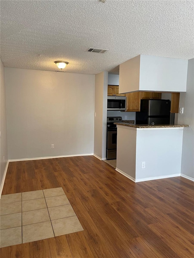 238 Afton Sq Unit 204, Altamonte Springs, FL 32714 - kitchen with appliances with stainless steel finishes, dark countertops, dark wood-style floors, a textured ceiling, and a peninsula