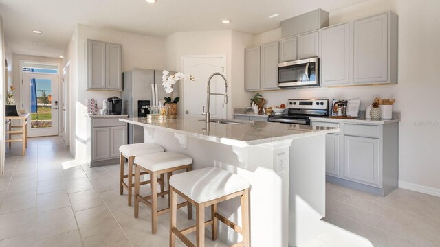 1325 June Lake Loop, Haines City, FL 33844 - kitchen with stainless steel appliances, a sink, gray cabinetry, an island with sink, and a breakfast bar area