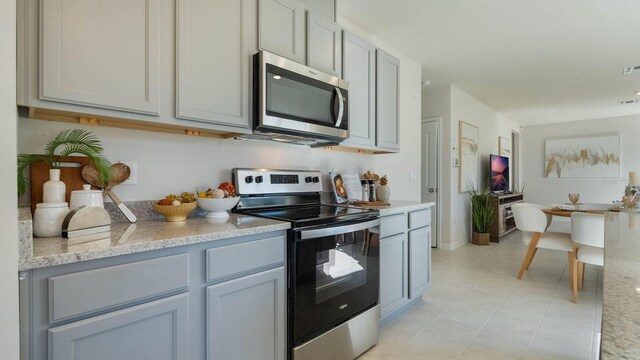1325 June Lake Loop, Haines City, FL 33844 - kitchen featuring stainless steel appliances, gray cabinets, light tile patterned floors, and light stone countertops
