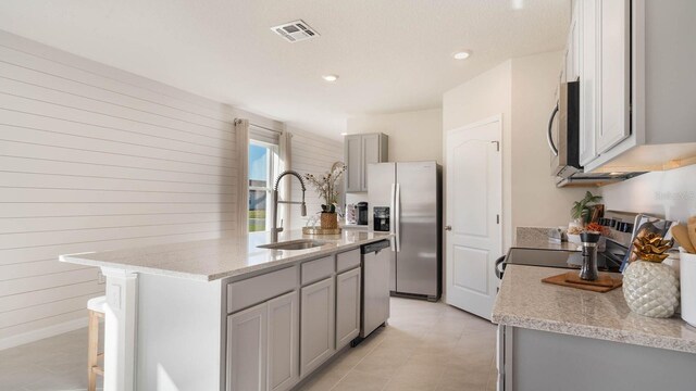 1325 June Lake Loop, Haines City, FL 33844 - kitchen with appliances with stainless steel finishes, a sink, gray cabinets, wood walls, and a kitchen island with sink