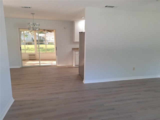 11282 SW 62nd Avenue Rd, Ocala, FL 34476 - spare room featuring baseboards, a chandelier, wood finished floors, and a wall mounted air conditioner