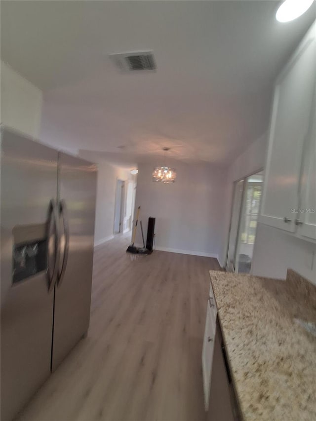11282 SW 62nd Avenue Rd, Ocala, FL 34476 - kitchen with stainless steel appliances, white cabinets, light wood-type flooring, a chandelier, and light stone countertops