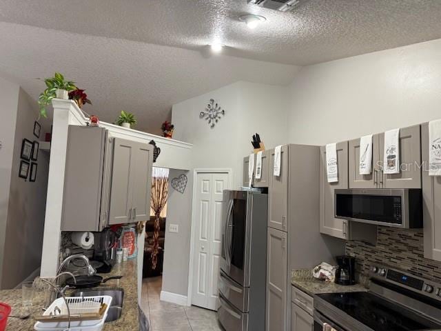 2514 Dovetail Dr, Ocoee, FL 34761 - kitchen featuring appliances with stainless steel finishes, vaulted ceiling, a sink, decorative backsplash, and a textured ceiling