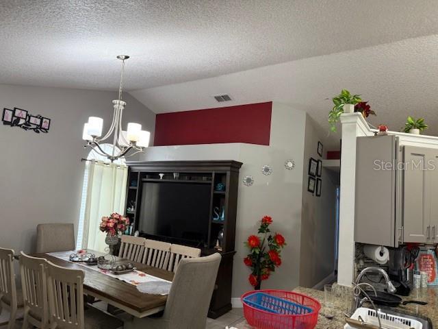 2514 Dovetail Dr, Ocoee, FL 34761 - dining room with a chandelier, vaulted ceiling, and light tile patterned floors