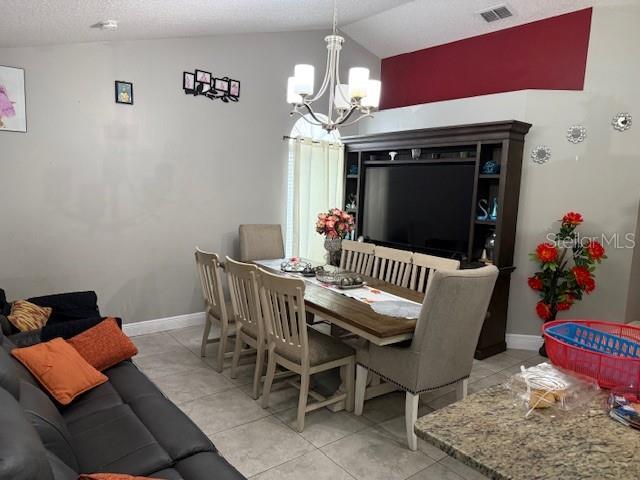 2514 Dovetail Dr, Ocoee, FL 34761 - dining area featuring a chandelier, vaulted ceiling, light tile patterned floors, and baseboards