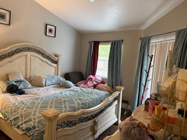 2514 Dovetail Dr, Ocoee, FL 34761 - bedroom featuring wood finished floors, lofted ceiling, and a textured ceiling