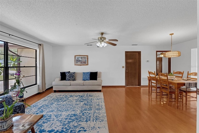 1830 W Clinton Dr, Saint Cloud, FL 34769 - living area featuring wood finished floors, a textured ceiling, a ceiling fan, and baseboards