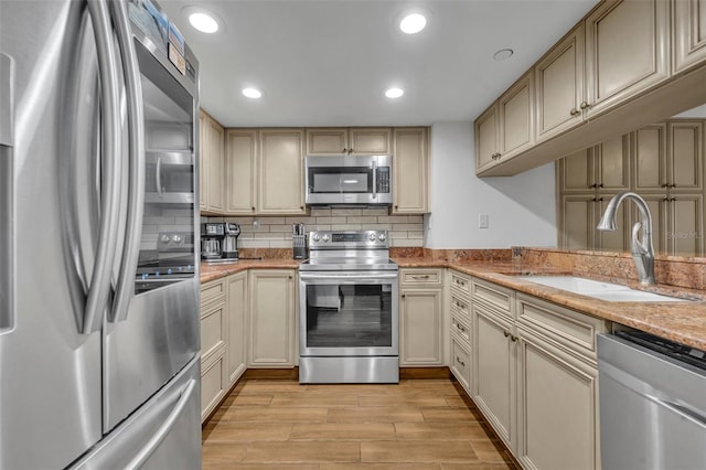 5207 S Atlantic Ave Unit 225, New Smyrna Beach, FL 32169 - kitchen featuring stainless steel appliances, a sink, tasteful backsplash, cream cabinetry, and light wood-style flooring