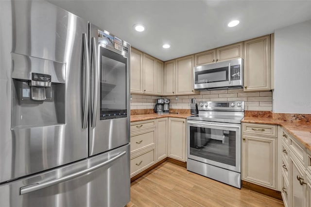 5207 S Atlantic Ave Unit 225, New Smyrna Beach, FL 32169 - kitchen featuring stainless steel appliances, cream cabinetry, light wood-type flooring, tasteful backsplash, and recessed lighting