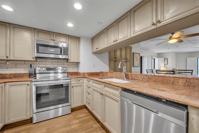 5207 S Atlantic Ave Unit 225, New Smyrna Beach, FL 32169 - kitchen with stainless steel appliances, a sink, light wood finished floors, cream cabinets, and decorative backsplash
