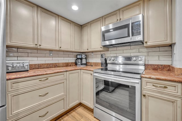 5207 S Atlantic Ave Unit 225, New Smyrna Beach, FL 32169 - kitchen with stainless steel appliances, cream cabinetry, tasteful backsplash, and light wood-type flooring