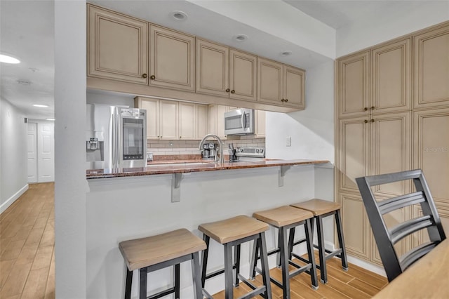 5207 S Atlantic Ave Unit 225, New Smyrna Beach, FL 32169 - kitchen with appliances with stainless steel finishes, cream cabinetry, light wood-style flooring, tasteful backsplash, and recessed lighting
