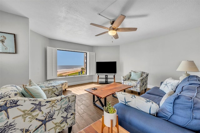 5207 S Atlantic Ave Unit 225, New Smyrna Beach, FL 32169 - living room featuring a textured ceiling, wood finished floors, a ceiling fan, and baseboards