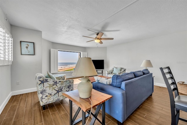 5207 S Atlantic Ave Unit 225, New Smyrna Beach, FL 32169 - living room with wood finish floors, ceiling fan, baseboards, and a textured ceiling