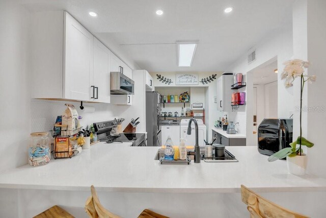 5635 Blue Shadows Ct Unit 3, Orlando, FL 32811 - kitchen with appliances with stainless steel finishes, a peninsula, white cabinetry, a kitchen breakfast bar, and recessed lighting