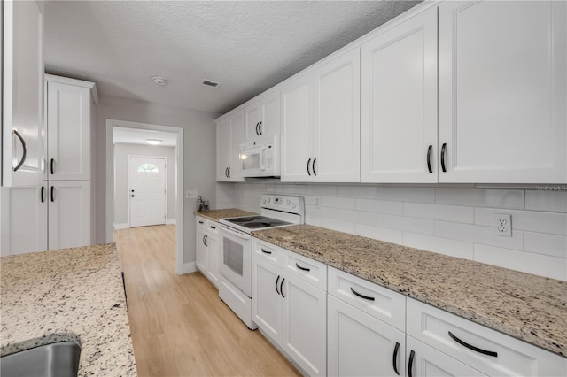 6 Cimmaron Dr, Palm Coast, FL 32137 - kitchen with white appliances, white cabinets, light wood-style floors, tasteful backsplash, and a textured ceiling