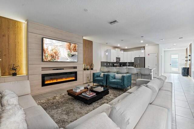 8833 Cruden Bay Ct, Davenport, FL 33896 - living room featuring a glass covered fireplace, light tile patterned floors, recessed lighting, and a textured ceiling