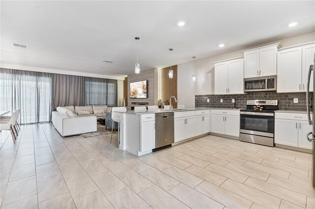 8833 Cruden Bay Ct, Davenport, FL 33896 - kitchen with stainless steel appliances, open floor plan, a peninsula, tasteful backsplash, and plenty of natural light