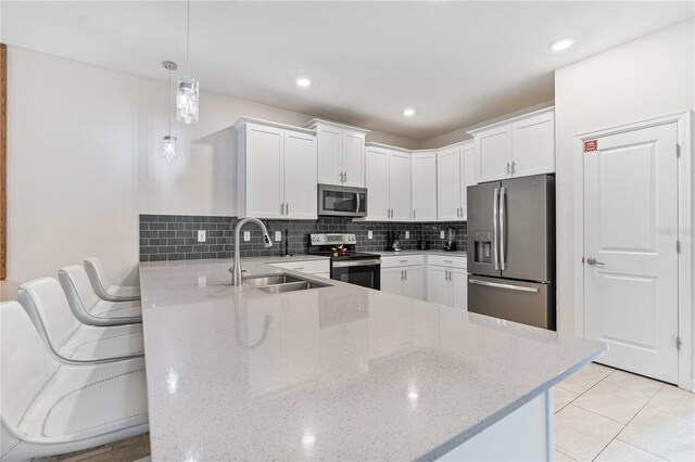 8833 Cruden Bay Ct, Davenport, FL 33896 - kitchen featuring appliances with stainless steel finishes, a sink, a peninsula, light stone counters, and white cabinetry