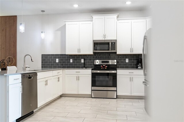8833 Cruden Bay Ct, Davenport, FL 33896 - kitchen featuring appliances with stainless steel finishes, a sink, a peninsula, backsplash, and white cabinets