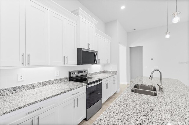 304 N Jungle Rd, Geneva, FL 32732 - kitchen featuring stainless steel appliances, a sink, white cabinetry, light stone countertops, and light wood-type flooring
