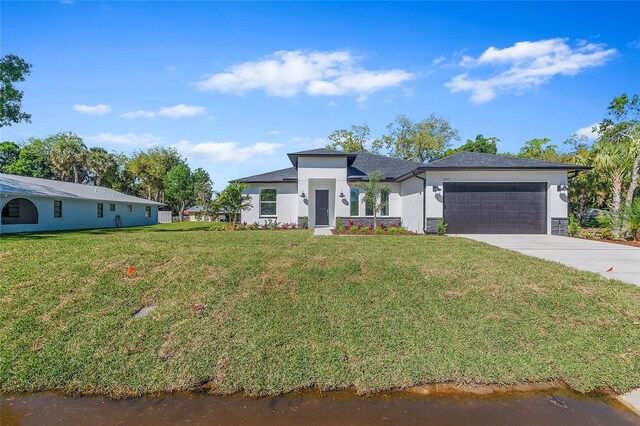 304 N Jungle Rd, Geneva, FL 32732 - view of front facade with a garage, stucco siding, a front lawn, driveway, and a water view