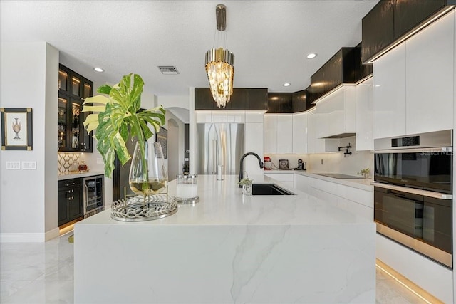 3924 SW 189th Ave, Miramar, FL 33029 - kitchen featuring wine cooler, a sink, appliances with stainless steel finishes, white cabinets, and decorative backsplash