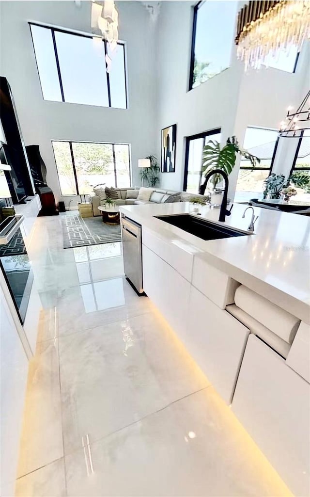 3924 SW 189th Ave, Miramar, FL 33029 - kitchen featuring a sink, a high ceiling, white cabinetry, stainless steel dishwasher, and a chandelier