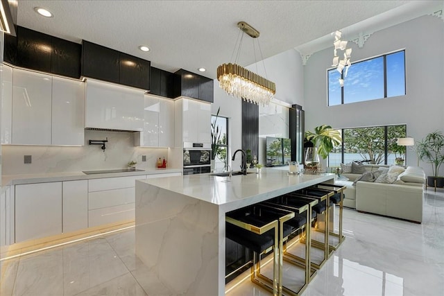 3924 SW 189th Ave, Miramar, FL 33029 - kitchen with light marble finish flooring, a chandelier, modern cabinets, black electric stovetop, and a sink