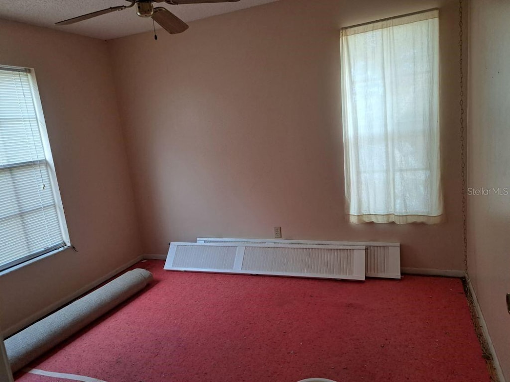 3607 Johnson Ct, Palm Harbor, FL 34684 - empty room featuring radiator heating unit, a ceiling fan, carpet floors, and baseboards