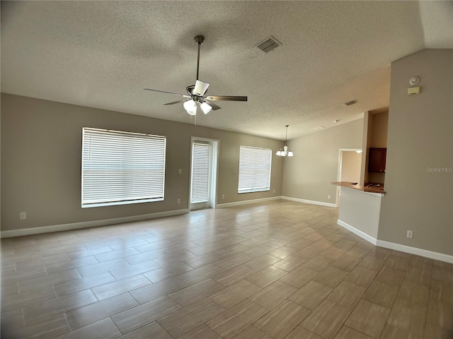 unfurnished living room with ceiling fan, a textured ceiling, a chandelier, vaulted ceiling, and baseboards