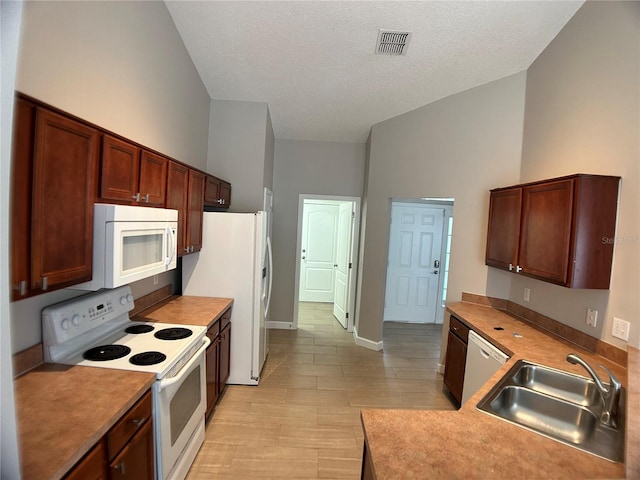 kitchen featuring white appliances, a sink, baseboards, light countertops, and a textured ceiling