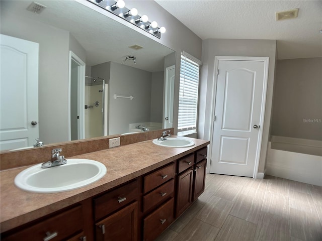 full bath featuring a walk in shower, a bath, double vanity, and a textured ceiling