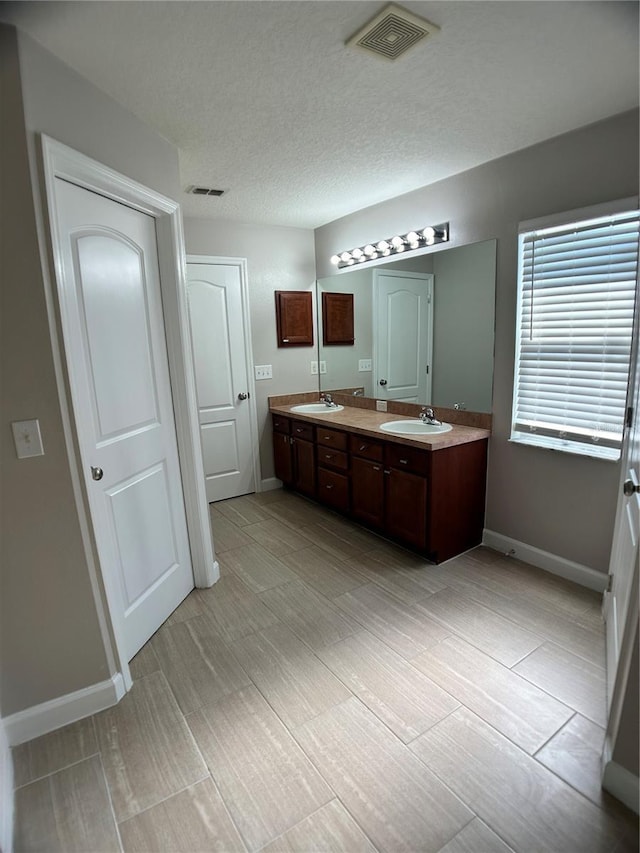 bathroom with baseboards and double vanity