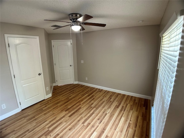 unfurnished bedroom with light wood-style floors, baseboards, a textured ceiling, and ceiling fan