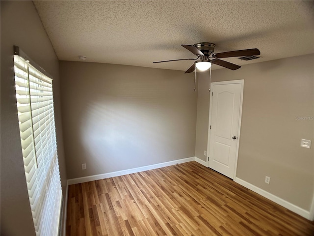 spare room featuring wood finished floors, ceiling fan, a textured ceiling, and baseboards