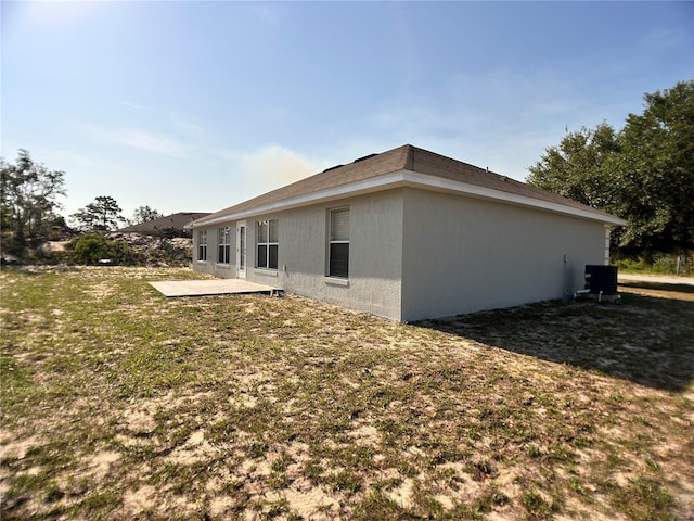 rear view of house with a patio, central air condition unit, and a lawn