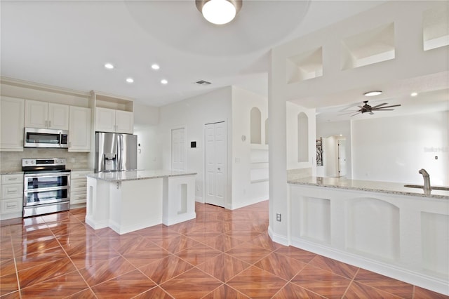 1254 Shelter Rock Rd, Orlando, FL 32835 - kitchen with appliances with stainless steel finishes, a ceiling fan, white cabinetry, light stone countertops, and recessed lighting