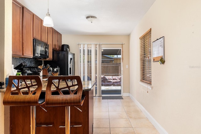 2272 Raeford Rd Unit A-3, Orlando, FL 32806 - kitchen featuring black microwave, decorative backsplash, light tile patterned floors, baseboards, and decorative light fixtures