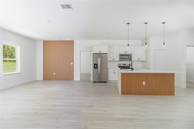 7229 N Gibralter Dr, Citrus Springs, FL 34434 - kitchen featuring appliances with stainless steel finishes, light wood finished floors, a center island with sink, white cabinets, and light countertops