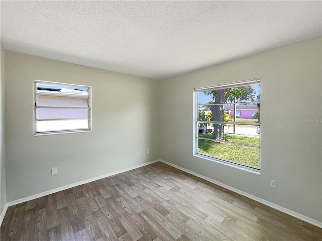 unfurnished room with wood finished floors, baseboards, and a textured ceiling
